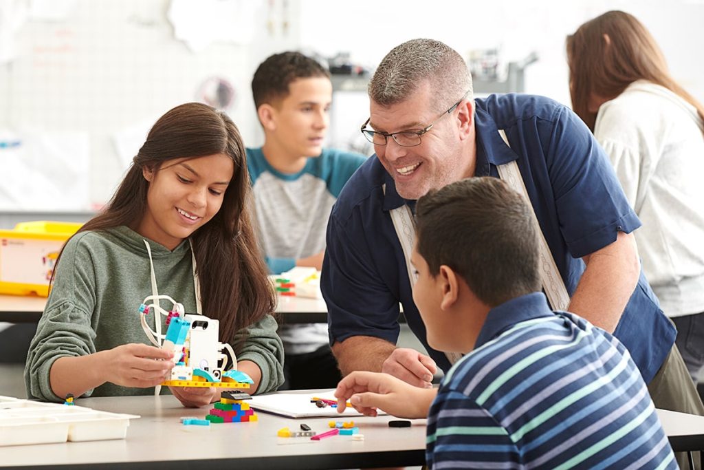 Joyful teacher observing their students creations using LEGO Education